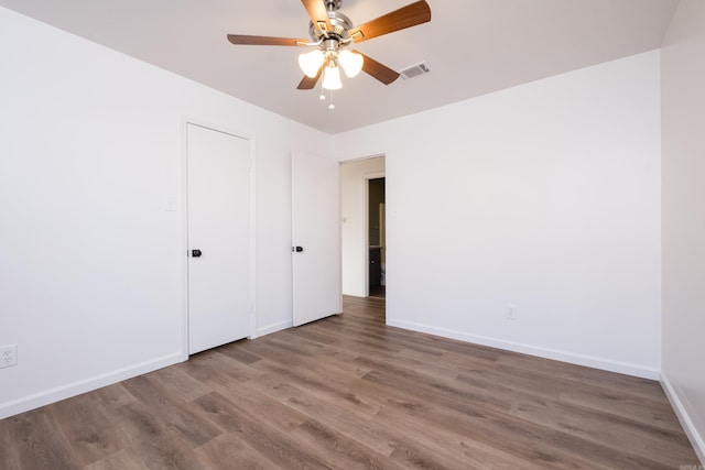 unfurnished bedroom with visible vents, a ceiling fan, baseboards, and wood finished floors