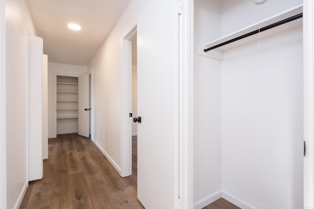 hallway featuring attic access, baseboards, and wood finished floors