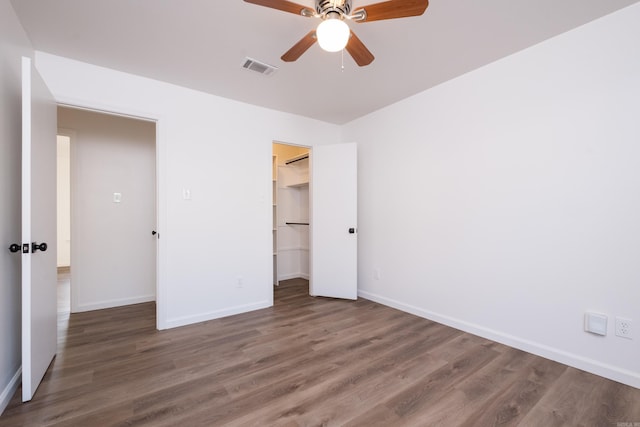 unfurnished bedroom featuring visible vents, baseboards, wood finished floors, and a spacious closet