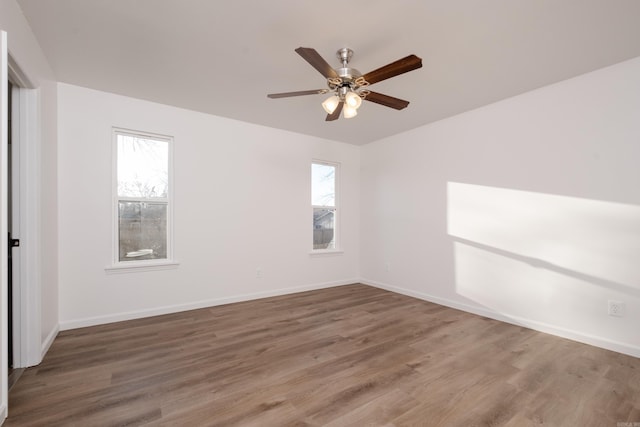 spare room featuring a ceiling fan, wood finished floors, and baseboards