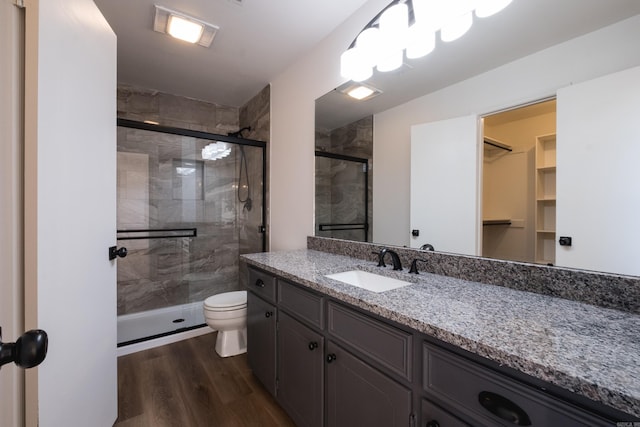 full bath with a stall shower, toilet, vanity, and wood finished floors