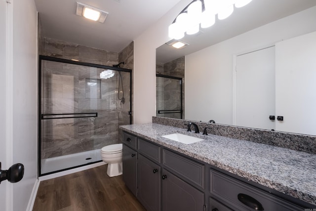 bathroom featuring vanity, a shower stall, toilet, and wood finished floors