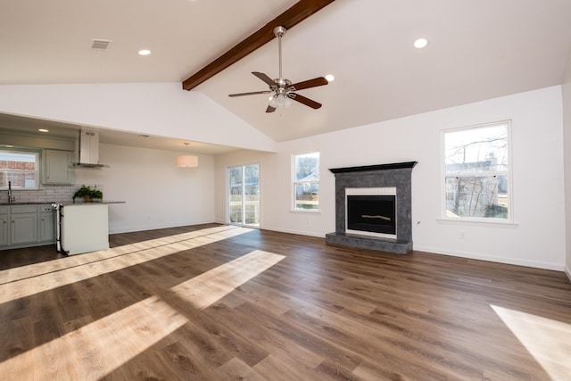 unfurnished living room featuring beam ceiling, visible vents, plenty of natural light, and dark wood-style flooring