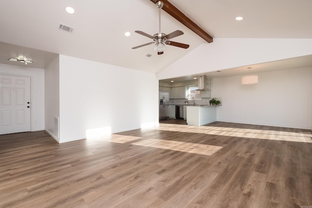 unfurnished living room with beamed ceiling, light wood-style flooring, baseboards, and a sink