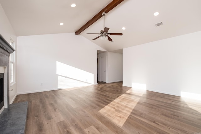 unfurnished living room featuring lofted ceiling with beams, visible vents, wood finished floors, and a tile fireplace