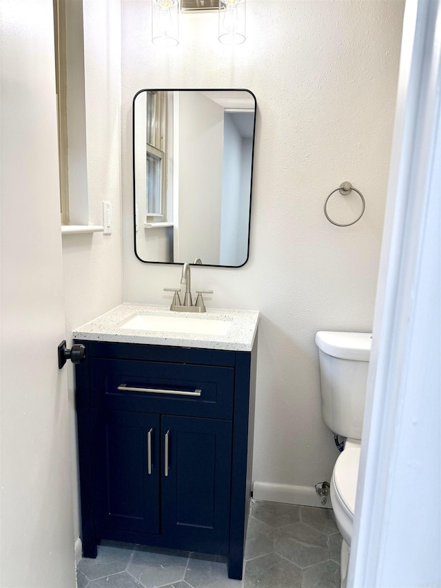 bathroom with tile patterned flooring, toilet, vanity, and baseboards