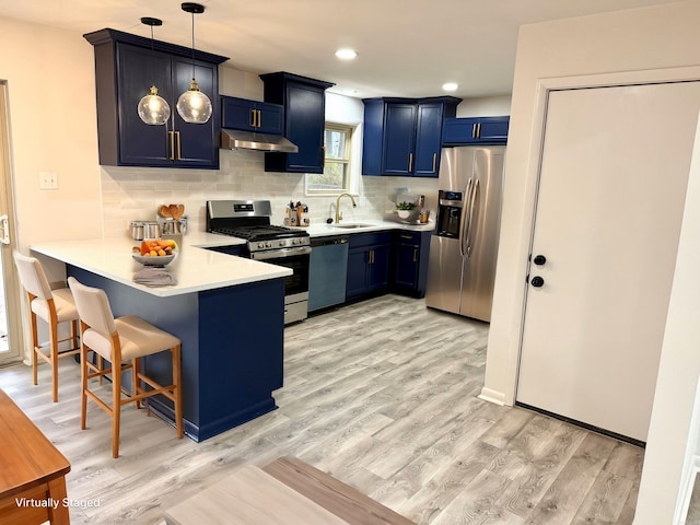 kitchen with a breakfast bar area, a peninsula, blue cabinetry, light countertops, and appliances with stainless steel finishes