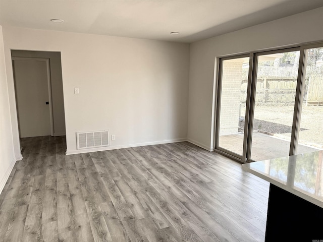 spare room with light wood finished floors, visible vents, and baseboards