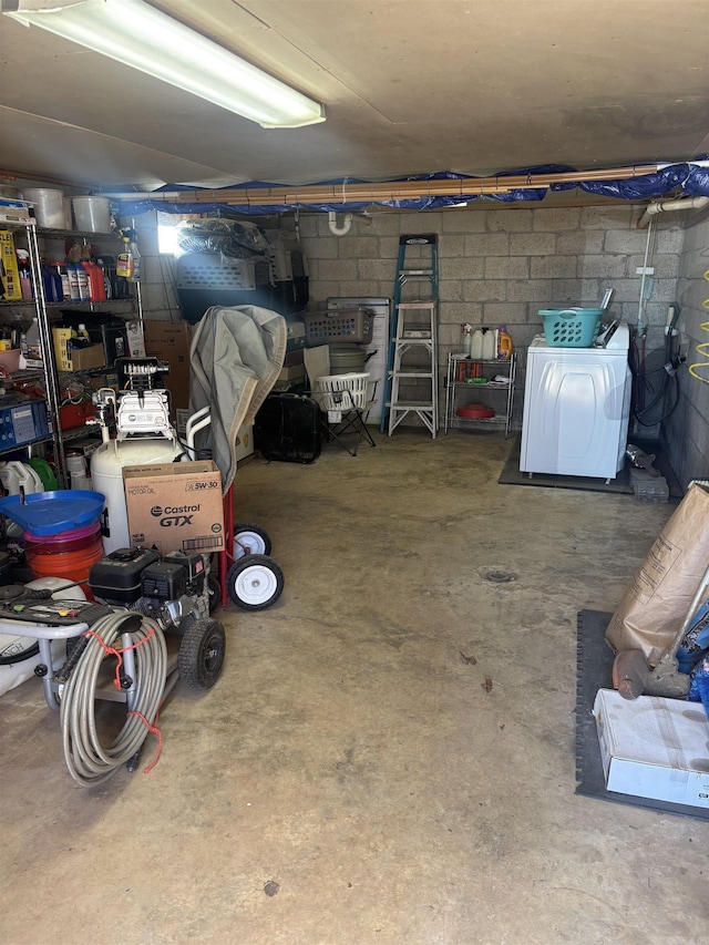 unfinished basement with washer / clothes dryer and concrete block wall