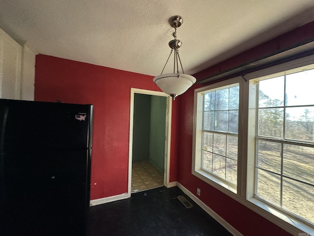 unfurnished dining area with visible vents, baseboards, and a textured ceiling