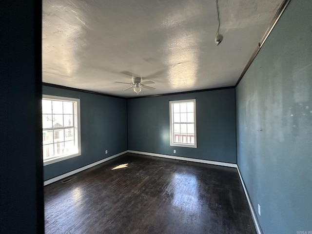 unfurnished room featuring visible vents, a ceiling fan, dark wood-type flooring, and baseboards