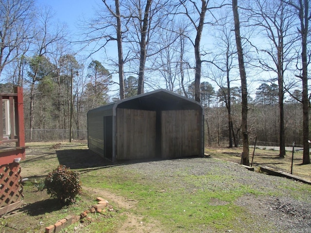 view of shed with dirt driveway and fence