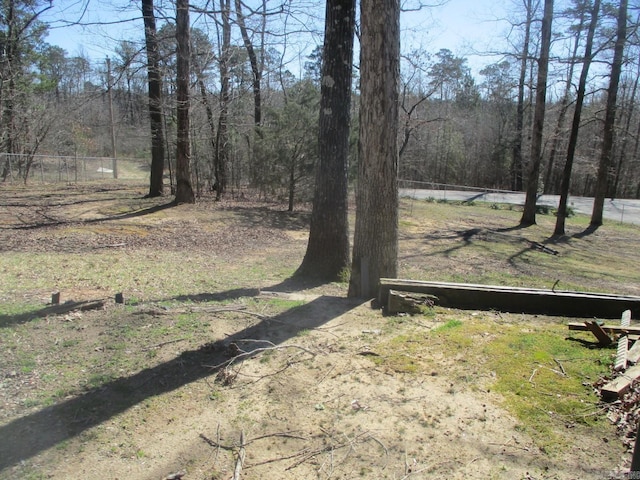 view of yard with a wooded view and fence