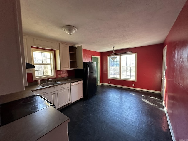 kitchen with a sink, dark countertops, freestanding refrigerator, dark floors, and white dishwasher