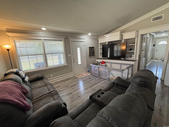 living area featuring visible vents, baseboards, vaulted ceiling, ornamental molding, and wood finished floors