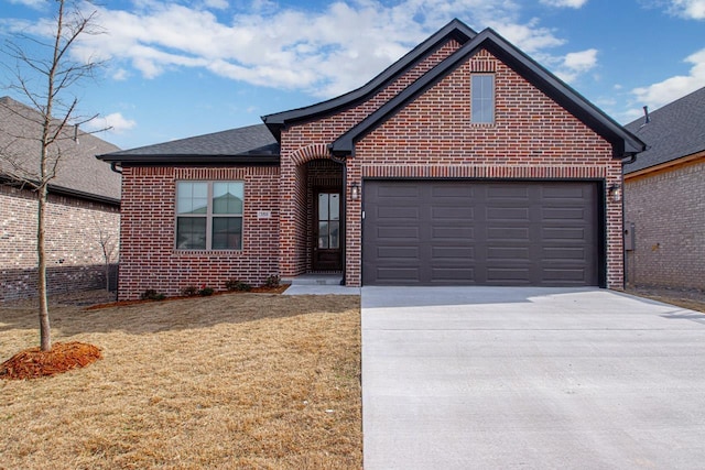 view of front of home featuring an attached garage, a shingled roof, concrete driveway, a front lawn, and brick siding