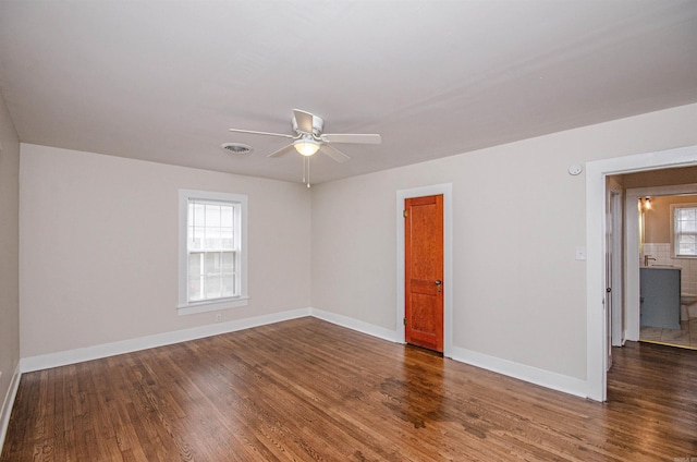 unfurnished room featuring baseboards, wood finished floors, visible vents, and a healthy amount of sunlight