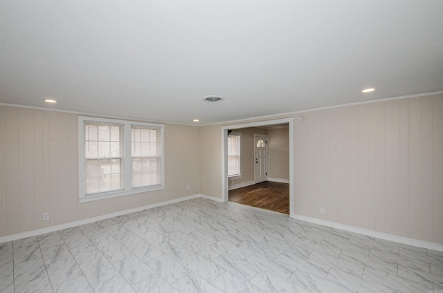 empty room with visible vents, a healthy amount of sunlight, marble finish floor, and crown molding