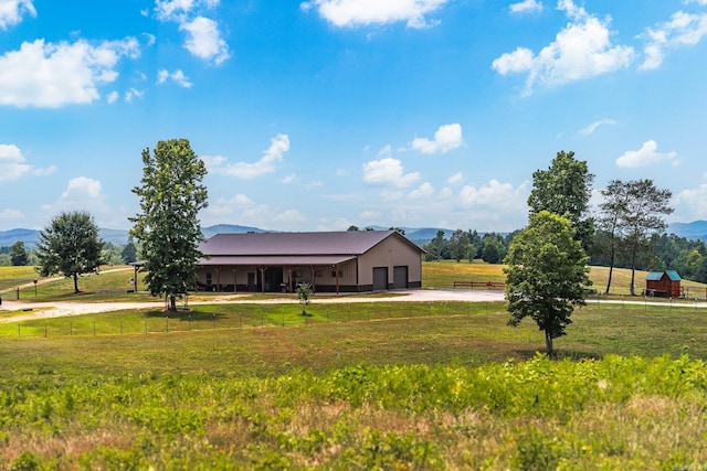 view of front of home with a rural view, a front lawn, fence, an outbuilding, and a mountain view