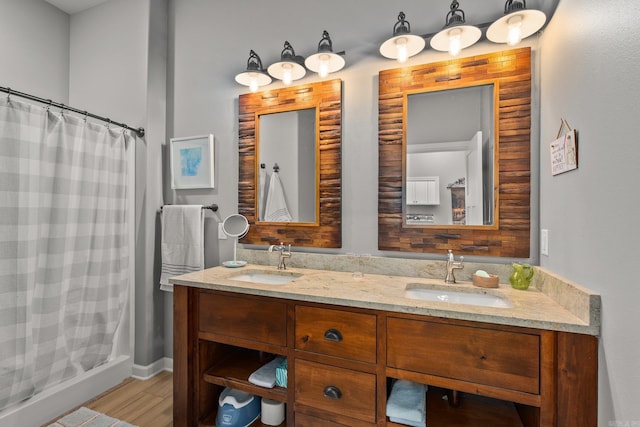 bathroom with double vanity, curtained shower, wood finished floors, and a sink