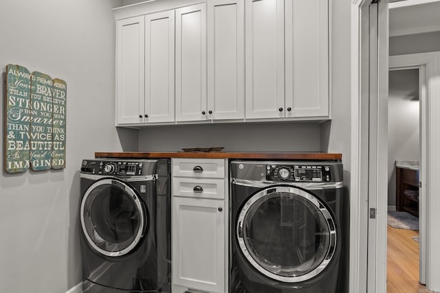 laundry area with light wood-style flooring, cabinet space, and washing machine and clothes dryer