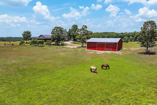 view of yard featuring a detached garage, a rural view, an outbuilding, and a pole building