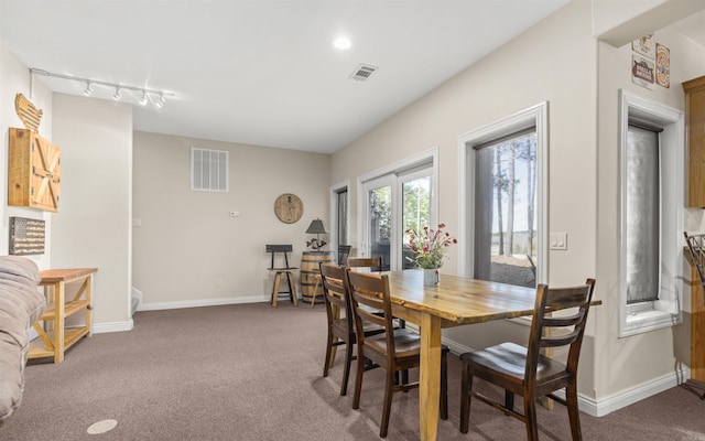 carpeted dining space with track lighting, baseboards, and visible vents
