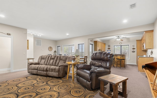 living area with visible vents, baseboards, and light carpet