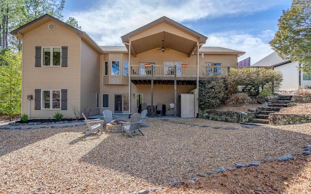 rear view of property with a deck, a ceiling fan, an outdoor fire pit, stairway, and a patio area
