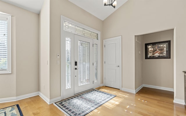 entryway with vaulted ceiling, light wood-style floors, and baseboards