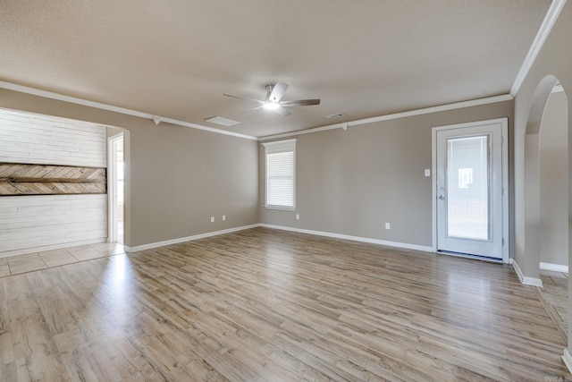 spare room featuring visible vents, a ceiling fan, arched walkways, crown molding, and light wood finished floors