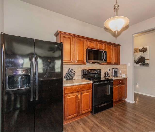 kitchen with tasteful backsplash, brown cabinets, black appliances, and dark wood-style flooring