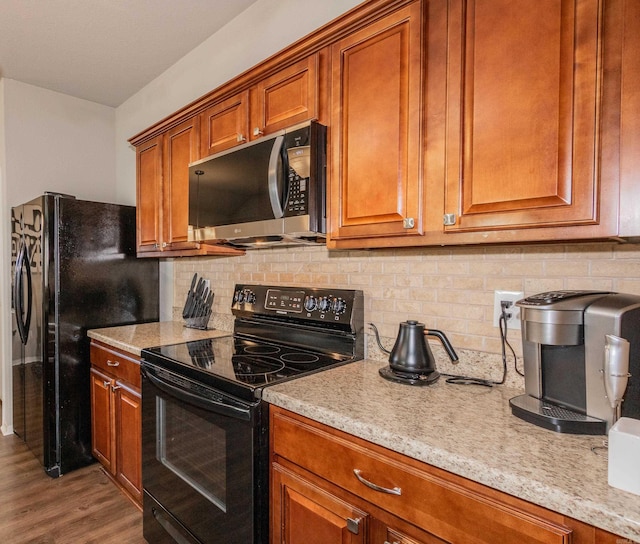 kitchen featuring decorative backsplash, black appliances, wood finished floors, and brown cabinetry