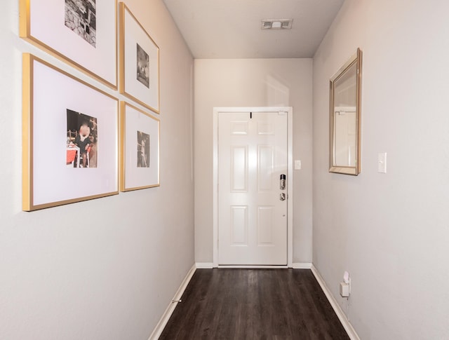 hall featuring dark wood finished floors, baseboards, and visible vents