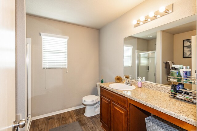 full bathroom featuring baseboards, toilet, a stall shower, wood finished floors, and vanity
