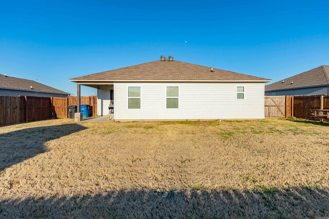 rear view of house with a lawn and a fenced backyard