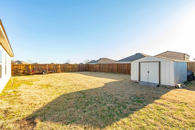 view of yard featuring an outdoor structure, a storage unit, and a fenced backyard