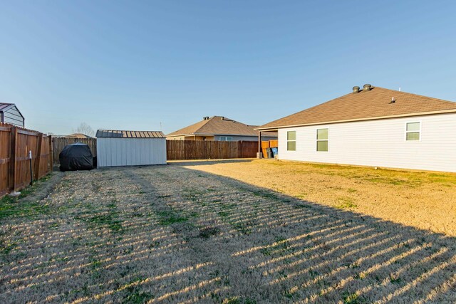 view of yard featuring a storage shed, a fenced backyard, and an outdoor structure