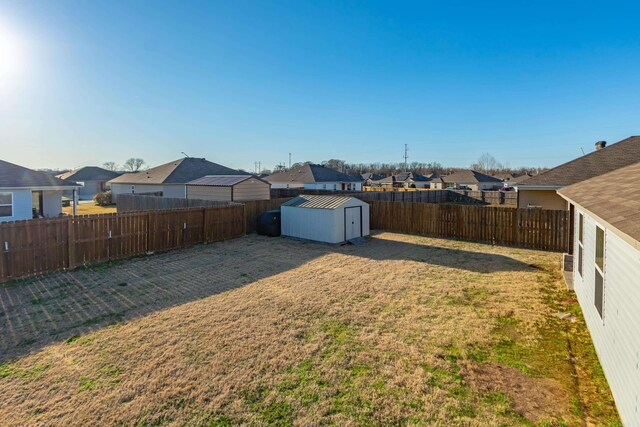 view of yard featuring an outbuilding, a residential view, a storage shed, and a fenced backyard