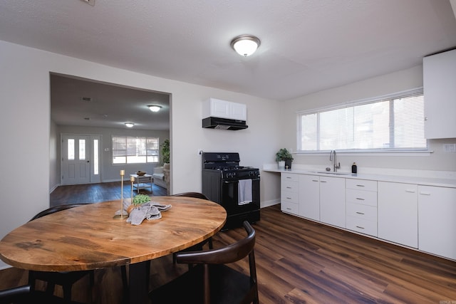 kitchen featuring dark wood-style floors, a sink, light countertops, black range with gas cooktop, and under cabinet range hood