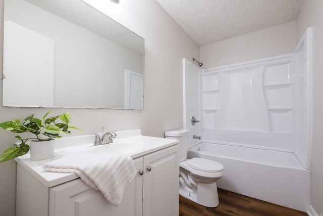 bathroom featuring vanity, wood finished floors,  shower combination, a textured ceiling, and toilet