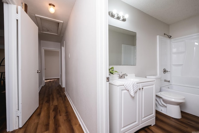 corridor featuring a sink, a textured ceiling, attic access, and dark wood finished floors