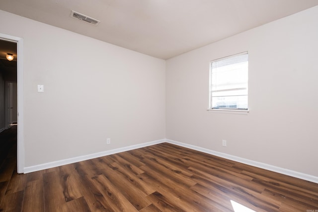 empty room featuring visible vents, baseboards, and dark wood-style flooring