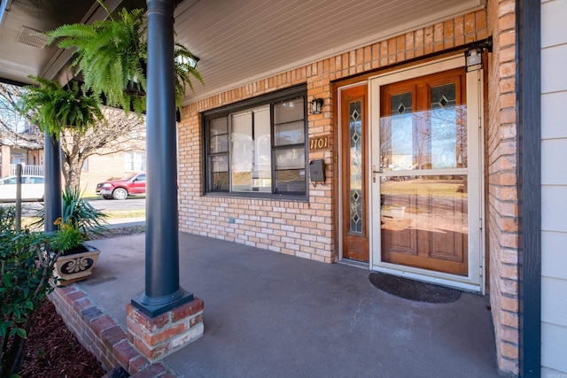 property entrance featuring brick siding and covered porch