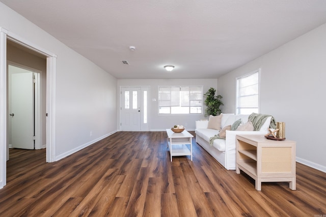 unfurnished living room featuring visible vents, baseboards, and dark wood-style flooring