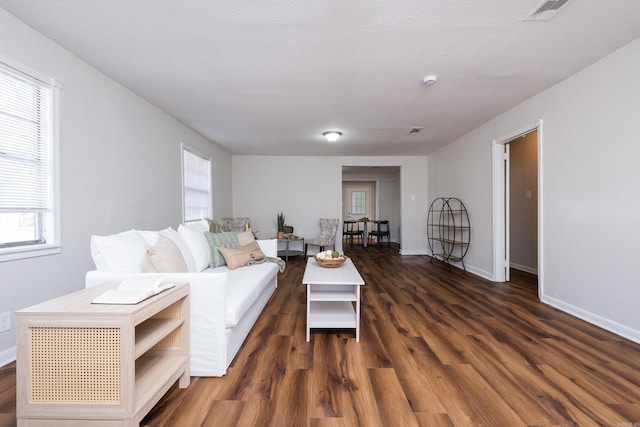 living room with visible vents, baseboards, and dark wood-style floors