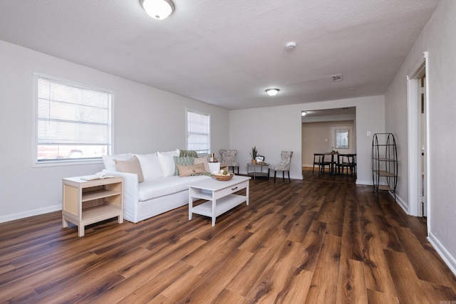 living room with a textured ceiling, baseboards, and wood finished floors