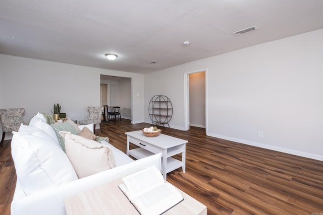 living area with visible vents, baseboards, a textured ceiling, and wood finished floors