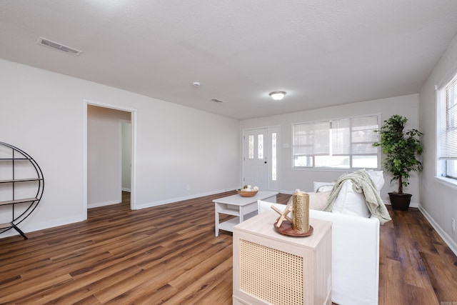 living room featuring visible vents, baseboards, and wood finished floors