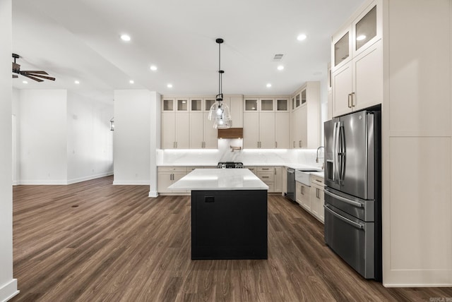 kitchen with backsplash, dark wood-style flooring, appliances with stainless steel finishes, and a center island